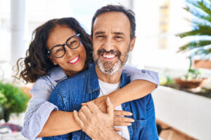 mature couple with their arms around each other showing off their dental implants