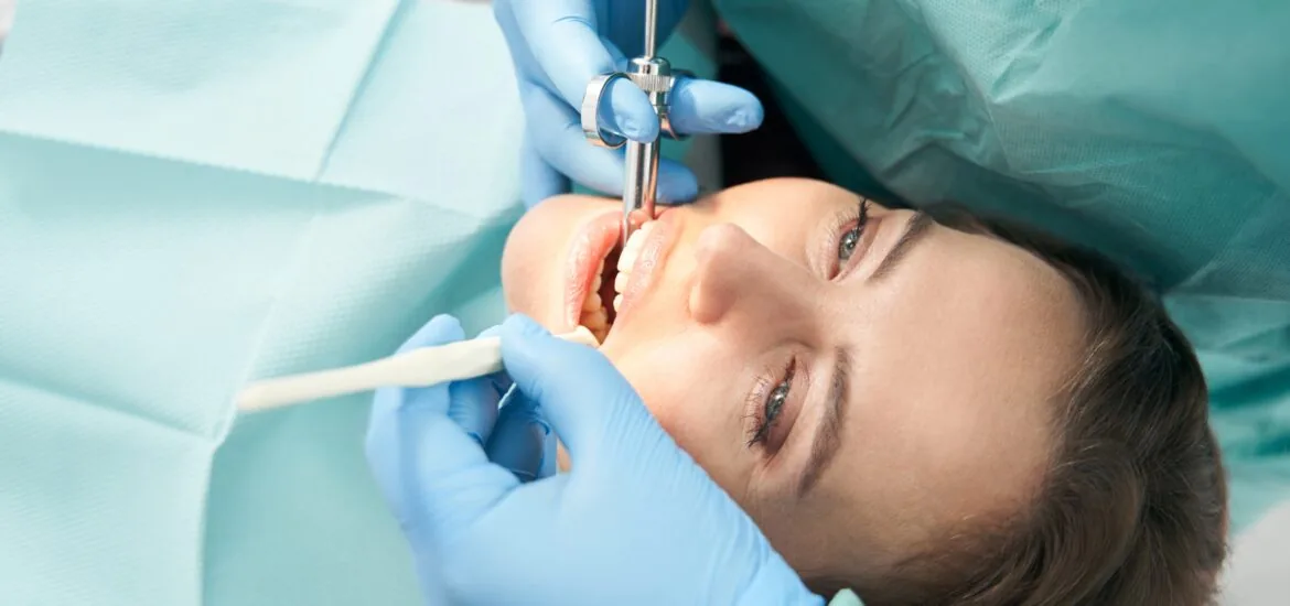 dentist in blue gloves preparing a female patient for a root canal