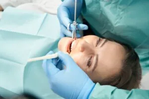 dentist in blue gloves preparing a female patient for a root canal