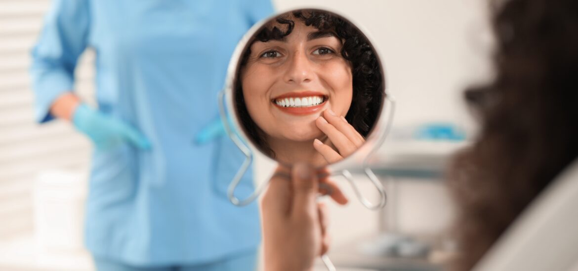 young woman looking in mirror, happy with new veneers