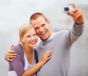 A young couple smiling while taking a photo together after teeth whitening treatments in White Plains.